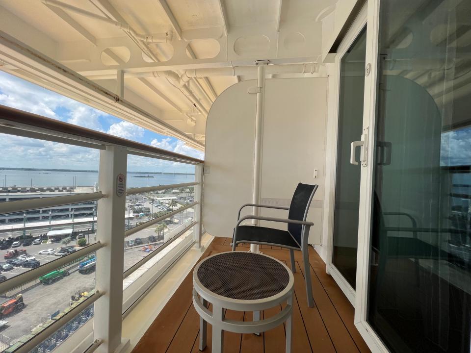 A small verandah with a chair and table. There is a sliding-glass door that leads back to the room. 