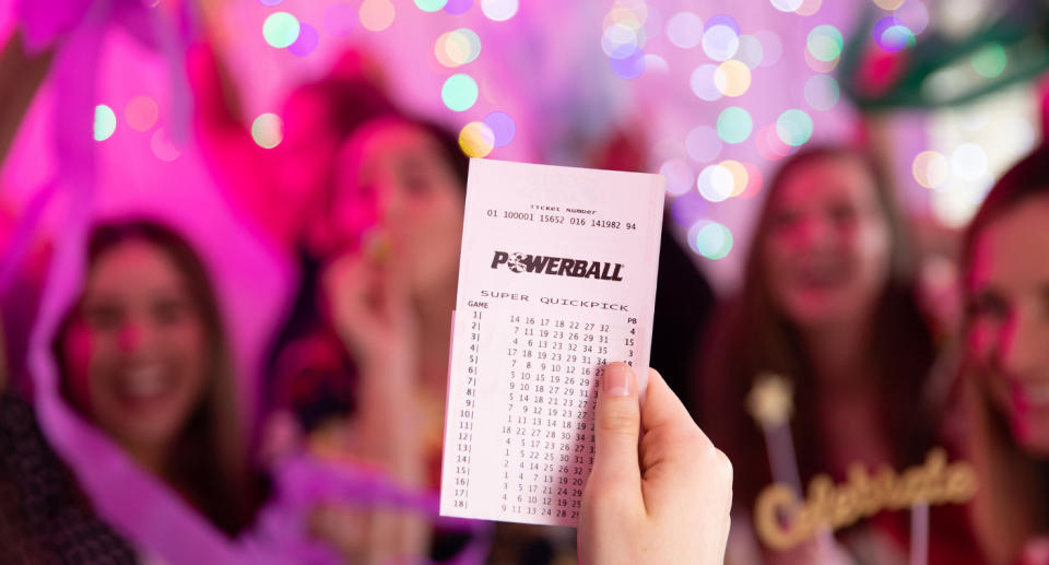 A person holds up a Powerball ticket.