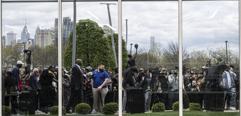 A larger crowd is reflected on a window during the unveiling of a statue of former Philadelphia 76ers NBA basketball player Allen Iverson, Friday, Apr 12, 2024, in Camden, N.J. (Jose F. Moreno/The Philadelphia Inquirer via AP)