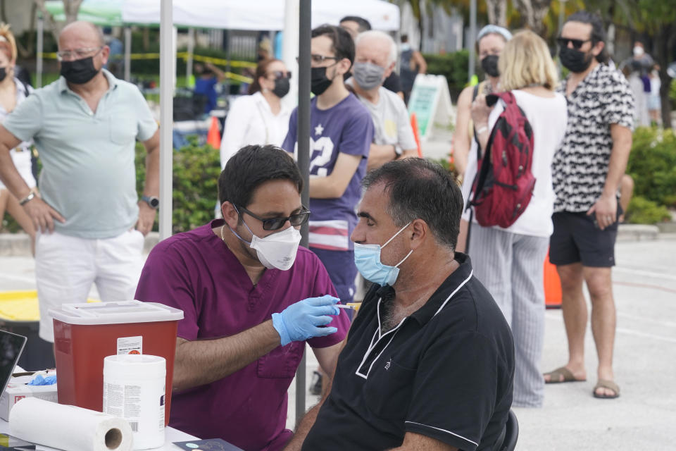 Carlos Anacleto closes his eyes as he receives the Pfizer COVID-19 vaccine from nurse Jorge Tase, as others wait their turn, Wednesday, Aug. 4, 2021, in Miami Beach, Fla. On Tuesday, the CDC added more than 50,000 new COVID-19 cases in the state over the previous three days, pushing the seven-day average to one the highest counts since the pandemic began, an eightfold increase since July 4. (AP Photo/Marta Lavandier)