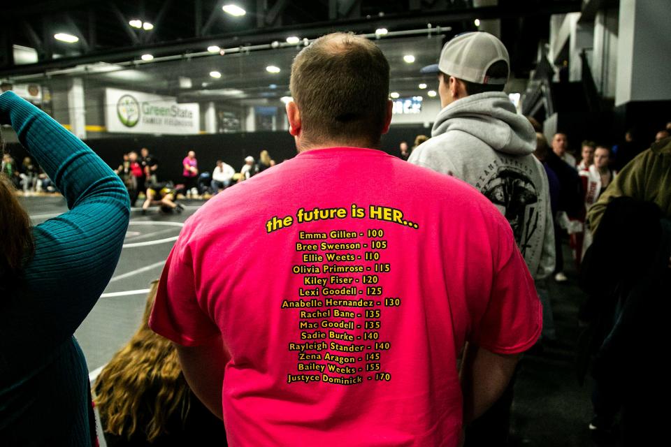 A fan wears a shirt reading "The future is HER..." while watching a match during the first session of the Iowa Wrestling Coaches and Officials Association (IWCOA) girls' state wrestling tournament, Friday, Jan. 21, 2022, at the Xtream Arena in Coralville, Iowa.