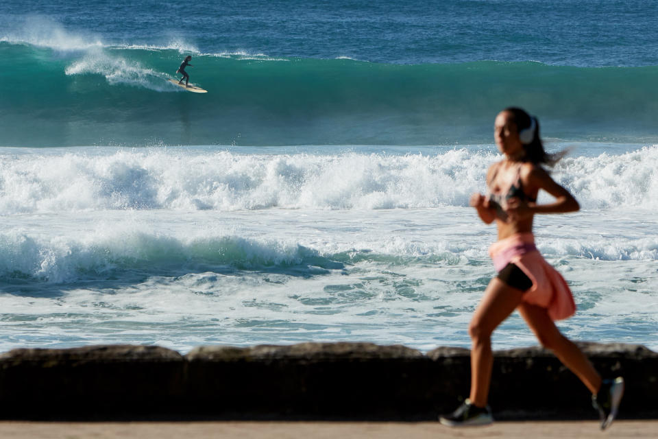 A woman runs on Manly beach in the early morning as daylight savings comes to an end.