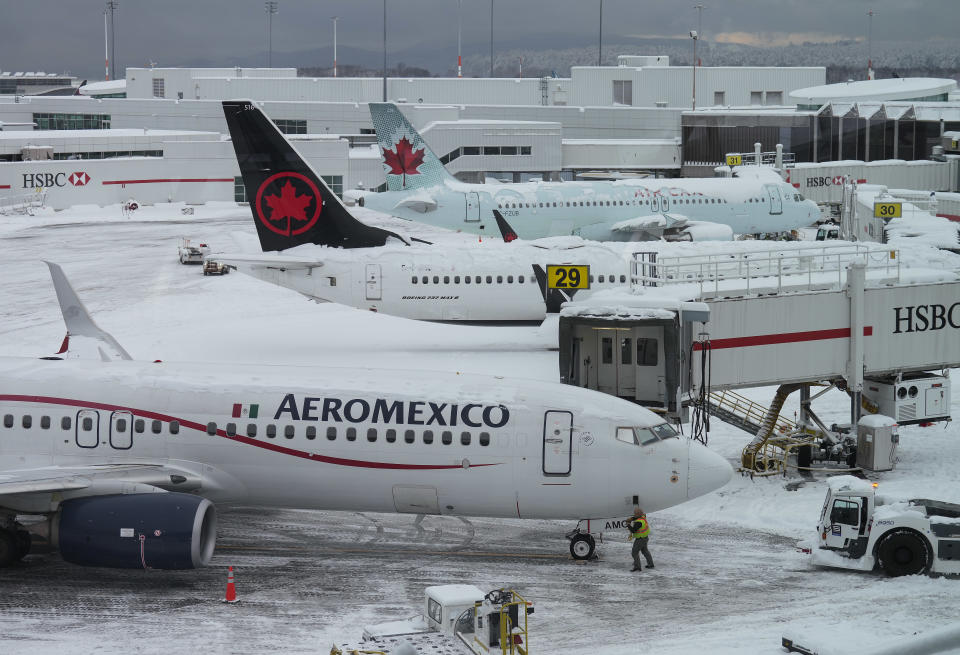 Aircraft are seen parked at gates at Vancouver International Airport after a snowstorm crippled operations leading to cancellations and major delays, in Richmond, B.C., on Tuesday, December 20, 2022. THE CANADIAN PRESS/Darryl Dyck