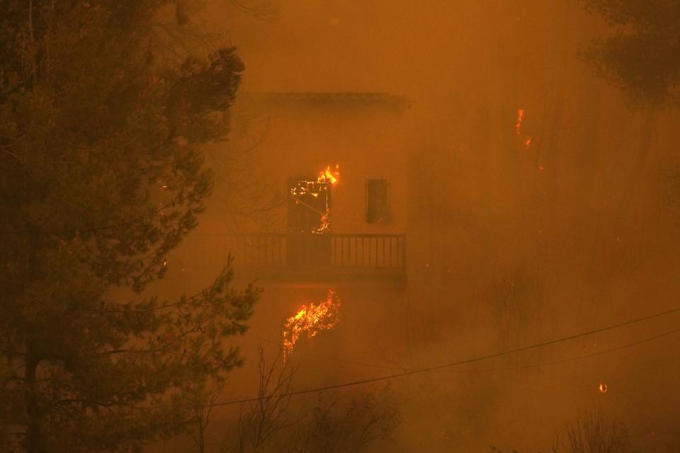 Flames burn a house at Pefki village on Evia island, about 189 kilometers (118 miles) north of Athens, Greece, Sunday, Aug. 8, 2021. Pillars of billowing smoke and ash are blocking out the sun above Greece's second-largest island as a days-old wildfire devours pristine forests and triggers more evacuation alerts. (AP Photo/Petros Karadjias)