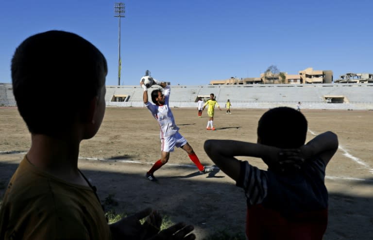 Syrians watch a football match on April 16, 2018 between local teams at a stadium in Raqa that the Islamic State group once used as a prison