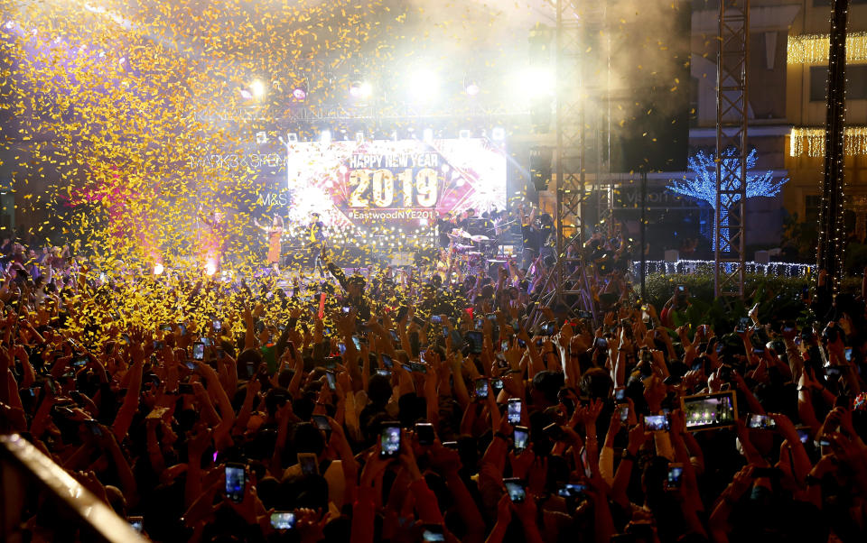 In this Tuesday, Jan. 1, 2019, file photo, confetti rains down on revelers at the Eastwood Shopping Mall as Filipinos welcome the New Year, in suburban Quezon city northeast of Manila, Philippines. Filipinos welcome the New Year with the loudest noise possible including setting off powerful firecrackers in one of Asia's most violent celebrations. (AP Photo/Bullit Marquez, File)