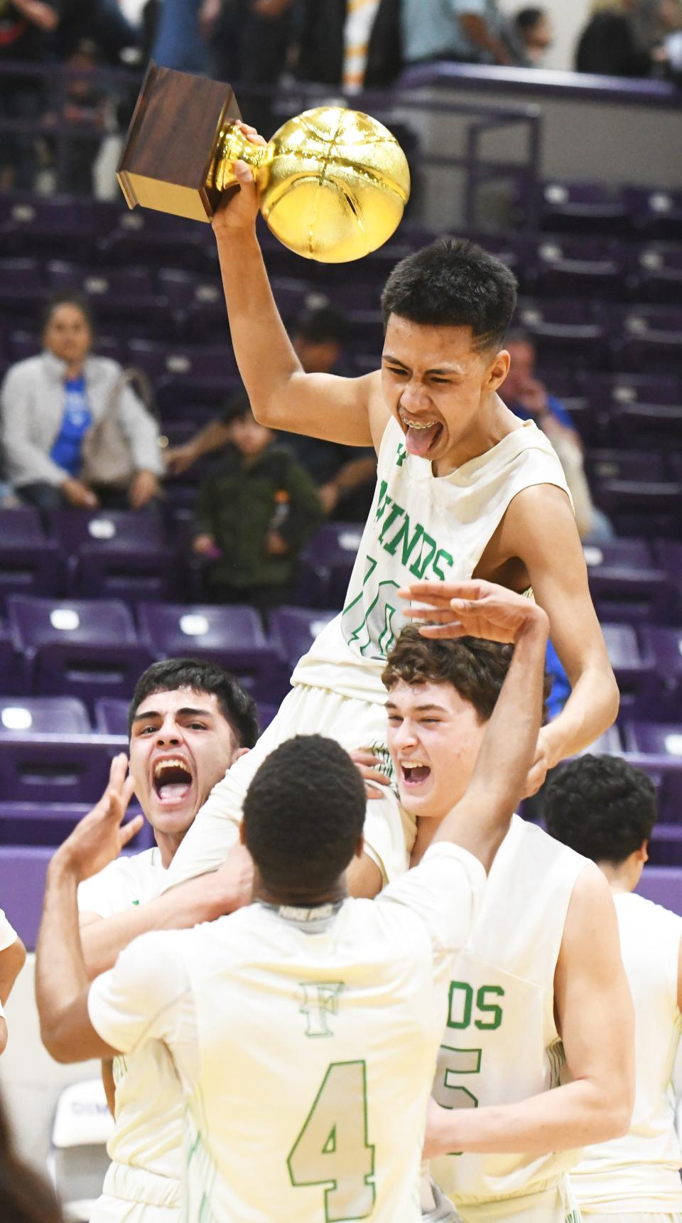Floydada's Abran Castillo lifts the trophy as teammates lift him up after beating Farwell in a Region I-2A quarterfinal Tuesday, Feb. 28, 2023, at Kenneth Cleveland Gymnasium in Dimmitt.