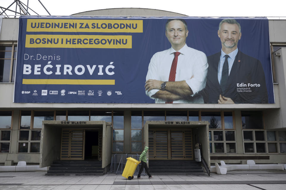 A man walks beneath an election poster of Denis Becirovic ahead of the upcoming elections in Sarajevo, Bosnia, Tuesday, Sept. 27, 2022. Bosnia's upcoming general election could be about the fight against corruption and helping its ailing economy. But at the time when Russia has a strong incentive to reignite conflict in the small Balkan nation, the Oct 2. vote appears set to be an easy test for long-entrenched nationalists who have enriched cronies and ignored the needs of the people. (AP Photo/Armin Durgut)