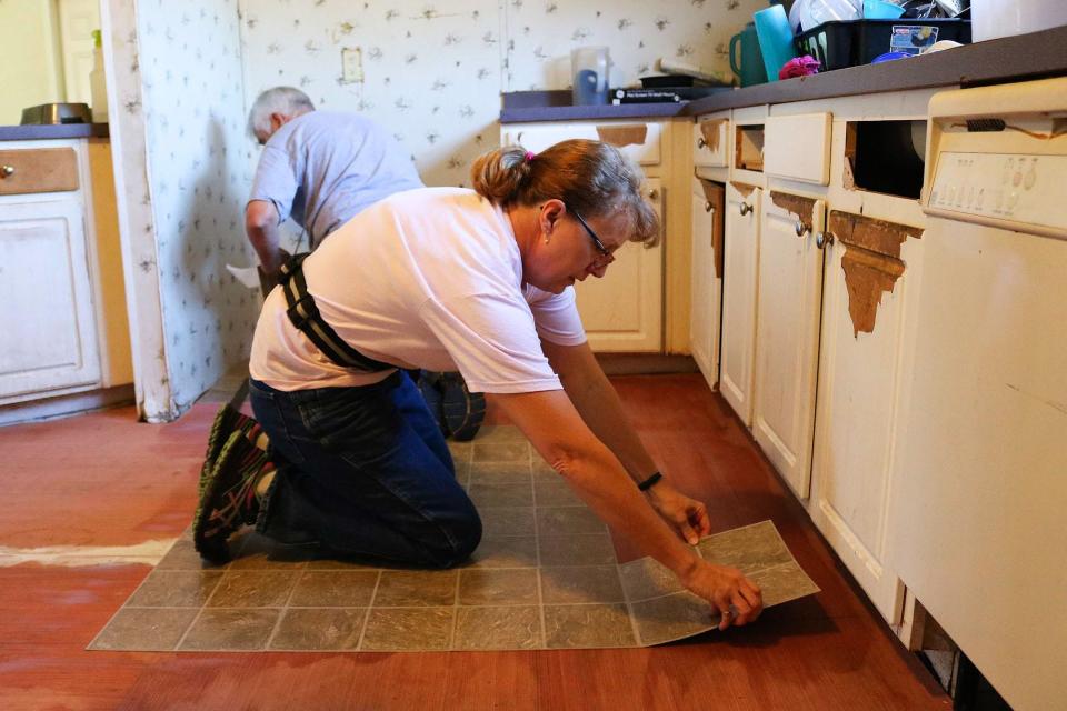 Volunteers lay kitchen tile in a veteran’s home in 2017.