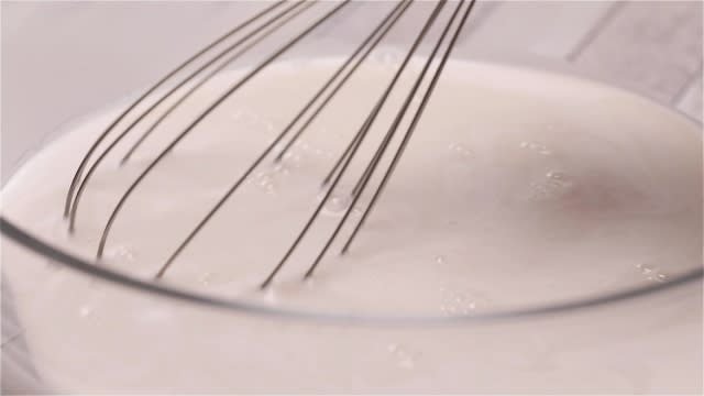 Mixing pandan sugar water with kueh lapis batter with whisk