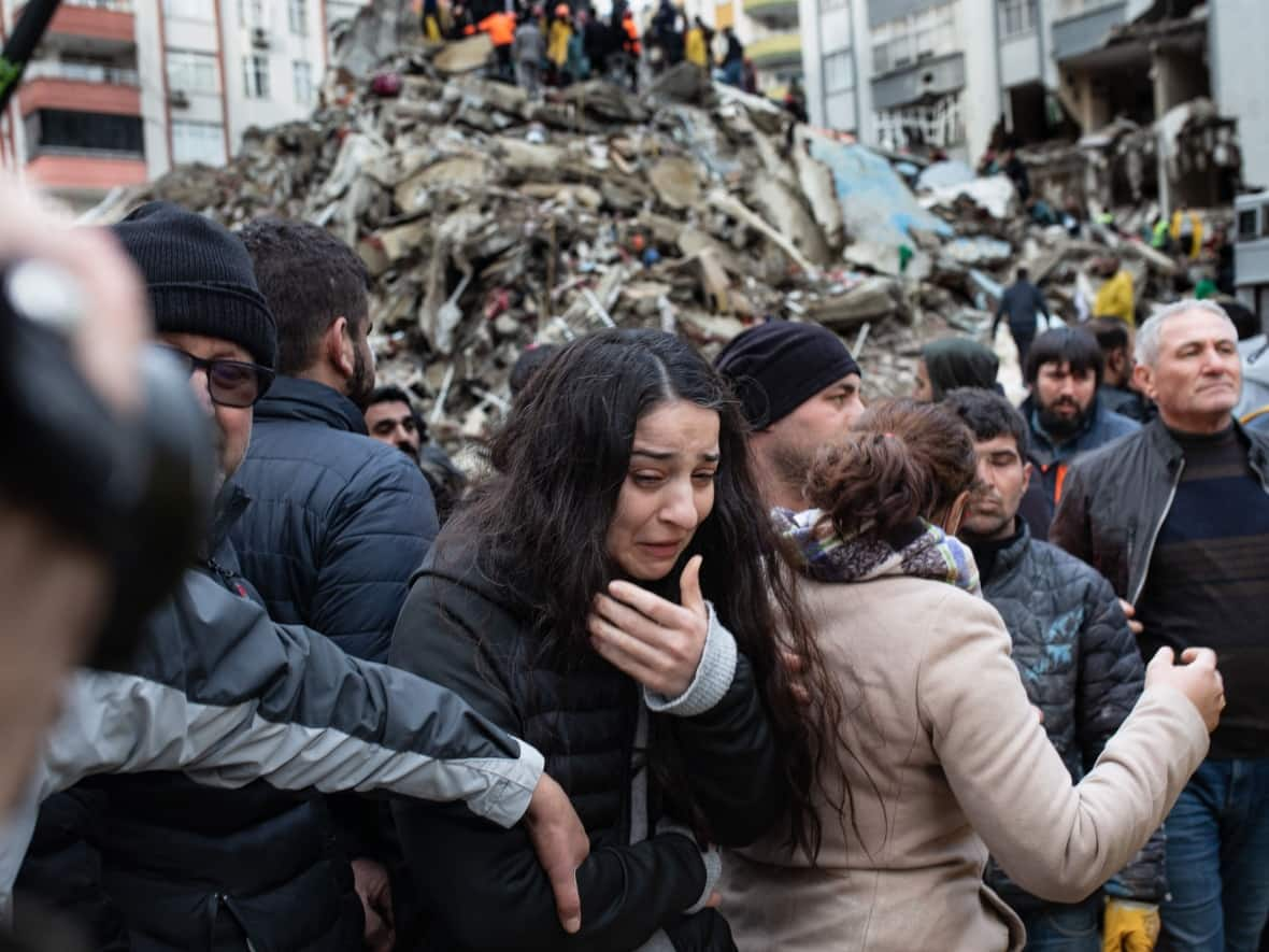 A woman reacts as rescuers search for survivors through the rubble of collapsed buildings in Adana, in southern Turkey.   (Can Erok/AFP/Getty Images - image credit)