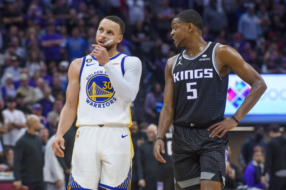Golden State Warriors guard Stephen Curry (30) and Sacramento Kings guard De'Aaron Fox (5) talk during a timeout during the second half of Game 2 in the first round of the NBA basketball playoffs in Sacramento, Calif., Monday, April 17, 2023. The Kings won 114-106.  (AP Photo/Randall Benton)