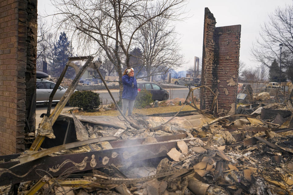 A woman reacts to seeing the remains of her mother's home destroyed by the Marshall Wildfire in Louisville, Colo., Friday, Dec. 31, 2021. (AP Photo/Jack Dempsey)