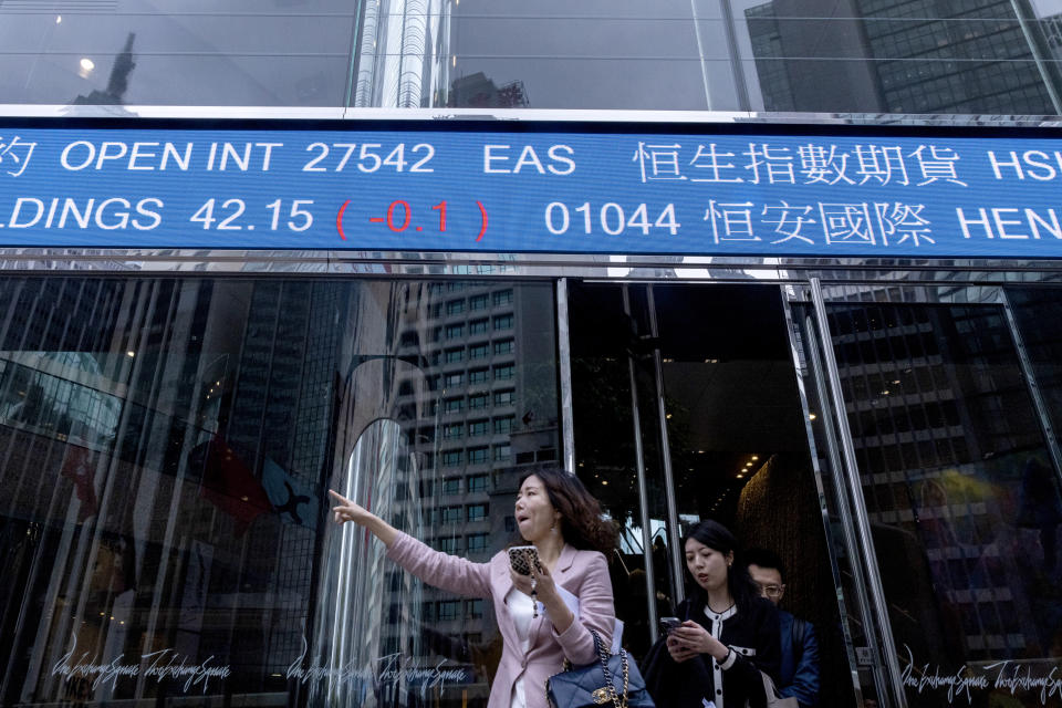 Pedestrians pass by the Hong Kong Stock Exchange electronic screen in Hong Kong, Thursday, March 30, 2023. Asian shares were mixed Thursday following a rally on Wall Street as worries over banks following the collapses of several lenders in recent weeks eased further. (AP Photo/Louise Delmotte)