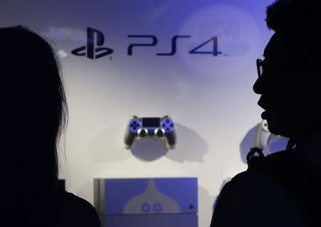 Visitors look at Sony Corp's PlayStation 4 game consoles and control pads displayed at a booth during the Tokyo Game Show 2014 in Makuhari, east of Tokyo in this September 18, 2014 file picture. REUTERS/Yuya Shino/Files