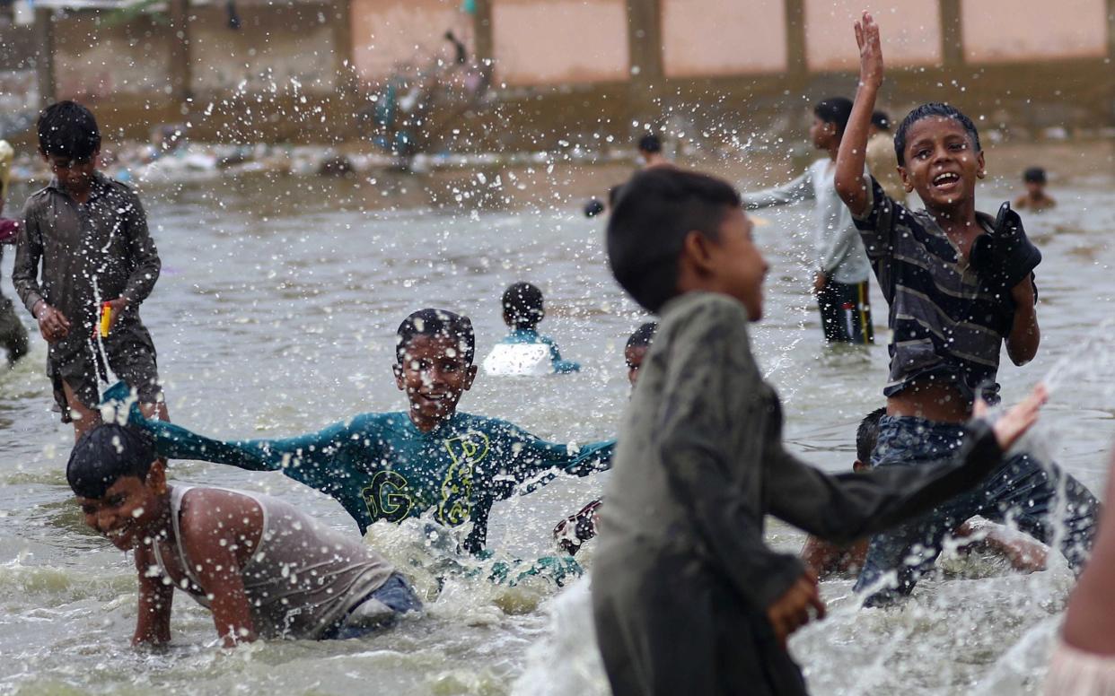 Children play in Karachi's dirty water amid monsoon rain. The amoeba Naegleria fowleri thrives in warm, fresh water and has killed 14 people in the Pakistani city this year - REX