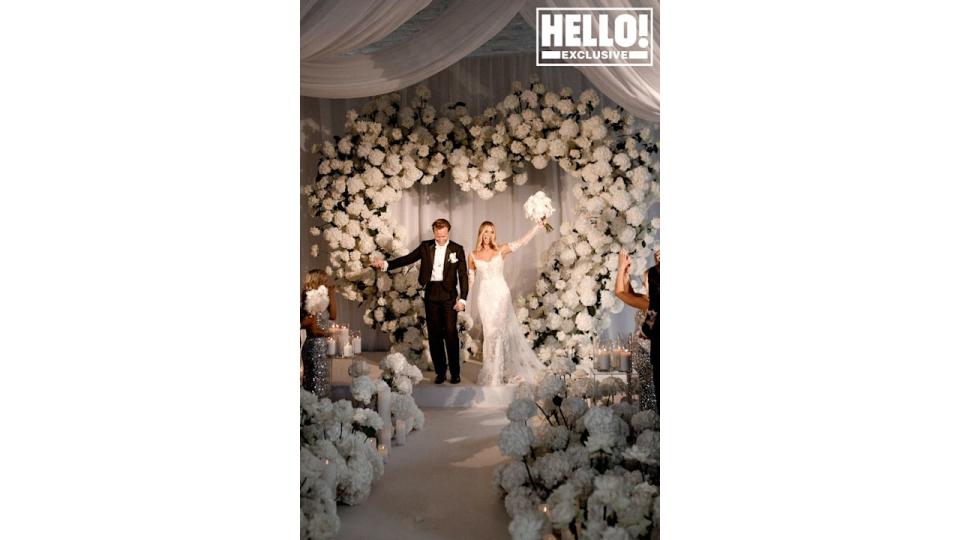 Olly Murs and Amelia Tank celebrating their wedding in front of white floral arrangement