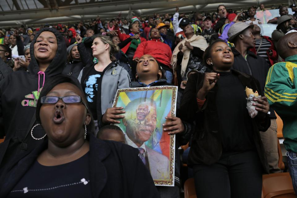 People shout out and hold posters during the memorial service for former South African president Nelson Mandela at the FNB Stadium in Soweto, near Johannesburg, South Africa, Tuesday Dec. 10, 2013. (AP Photo/Bernat Armangue)