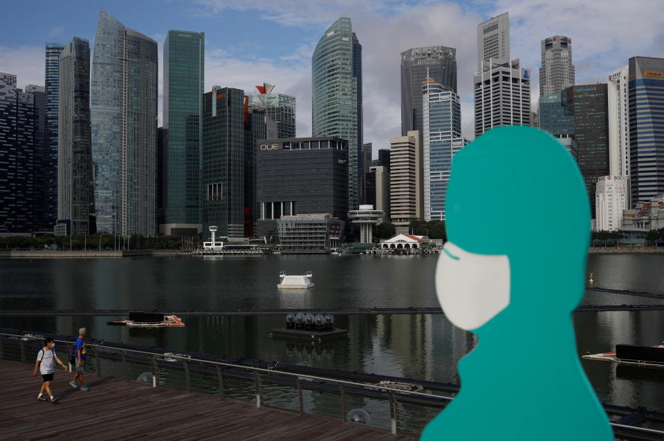 People wearing face masks pass a sign put up to encourage social distancing during the coronavirus disease (COVID-19) outbreak, at Marina Bay in Singapore, September 22, 2021. REUTERS/Edgar Su