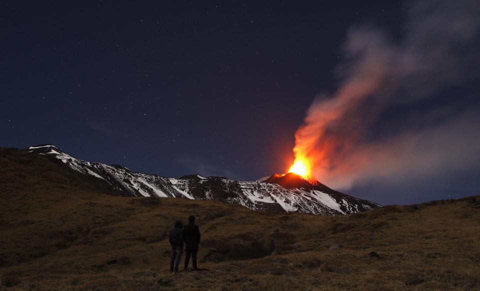 People watch Italy's Mount Etna, Europe's tallest and most active volcano, spewing lava as it erupts on the southern island of Sicily November 17, 2013. There were no reports of damage or evacuations in the area and the nearby airport of Catania was operating as normal, local media reported. It is the 16th time that Etna has erupted in 2013. The south-eastern crater, formed in 1971, has been the most active in recent years. REUTERS/Antonio Parrinello (ITALY - Tags: ENVIRONMENT SOCIETY TPX IMAGES OF THE DAY)