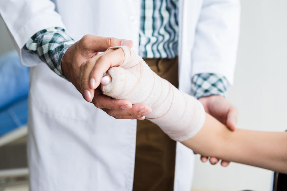 A doctor is examining a person's bandaged arm