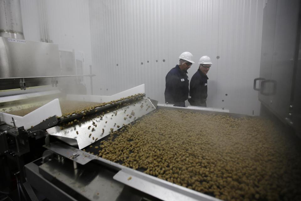 In this Tuesday, Oct. 1, 2013, photo, Freshpet workers walk past a conveyor belt of dog food at the company's pet food kitchen in Bethlehem, Pa. Upstart pet food maker Freshpet uses fresh meat, poultry and vegetables in a pricey, preservative-free product that requires refrigeration. Sales exceed $100 million. But the jury’s still out on whether food marketed as “fresh,” “organic” or “natural” helps pets lead longer lives. (AP Photo/Matt Slocum)