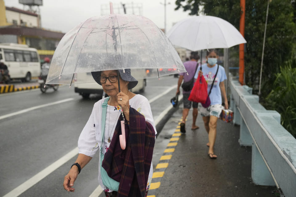 Women uses umbrella during enhanced rains brought about by Typhoon Doksuri on Thursday, July 27, 2023, in Marikina city, Philippines. Typhoon Doksuri lashed northern Philippine provinces with ferocious wind and rain Wednesday, leaving several people dead and displacing thousands of others as it blew roofs off houses, flooded low-lying villages and triggered dozens of landslides, officials said. (AP Photo/Aaron Favila)