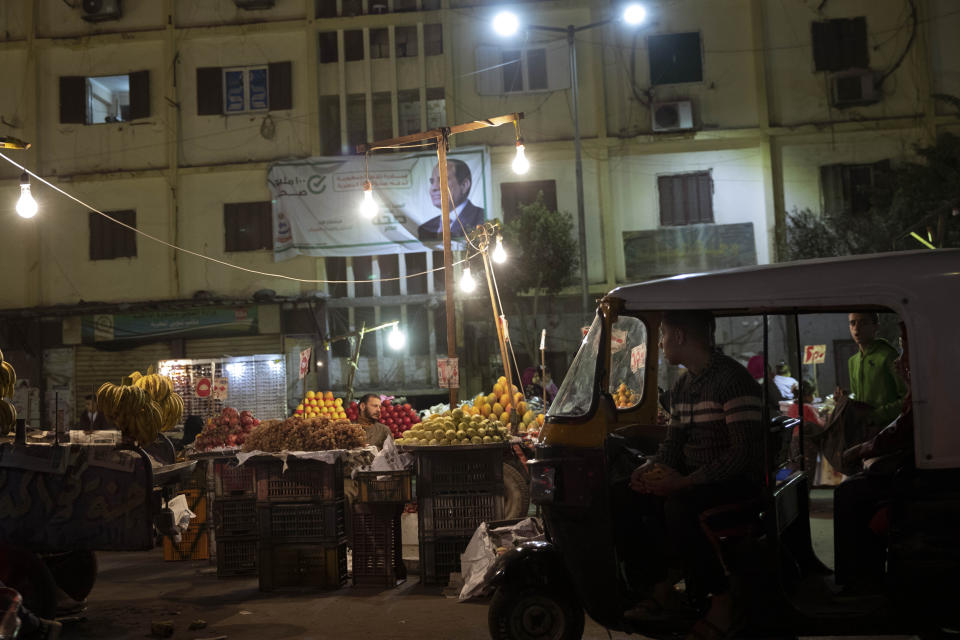 In this Nov. 19, 2019 photo, a tuk-tuk driver parks his tuk-tuk at a fruit market in Cairo, Egypt. Motorized rickshaws known as tuk-tuks have ruled the streets of Cairo’s slums for the past two decades hauling millions of Egyptians home every day. Now the government is taking its most ambitious stand yet against the polluting three-wheeled vehicles: to modernize the neglected transport system, it plans to replace tuk-tuks with clean-running minivans. (AP Photo/Nariman El-Mofty)