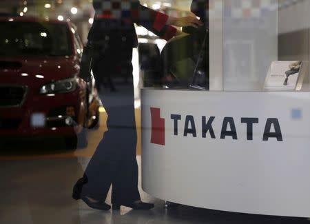 FILE PHOTO: A woman stands next to a logo of Takata Corp at a showroom for vehicles in Tokyo, Japan, November 6, 2015. REUTERS/Toru Hanai/File Photo