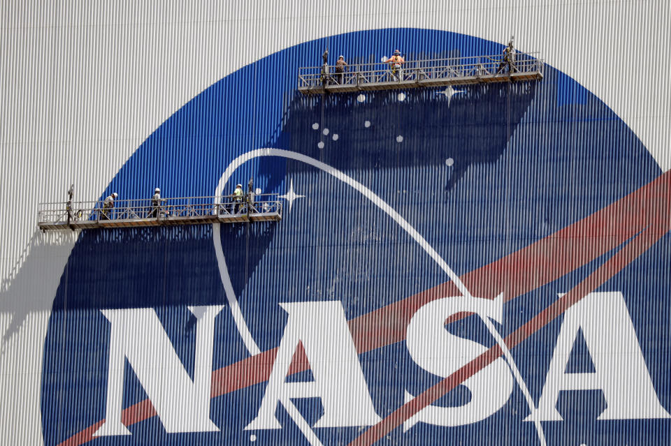 FILE - Workers near the top of the 526 ft. Vehicle Assembly Building at the Kennedy Space Center spruce up the NASA logo standing on scaffolds in Cape Canaveral, Fla., Wednesday, May 20, 2020. On Friday, Dec. 31, 2021, The Associated Press reported on stories circulating online incorrectly claiming NASA just hired 24 theologians to assess how the world would react if we discovered alien life. (AP Photo/John Raoux, File)