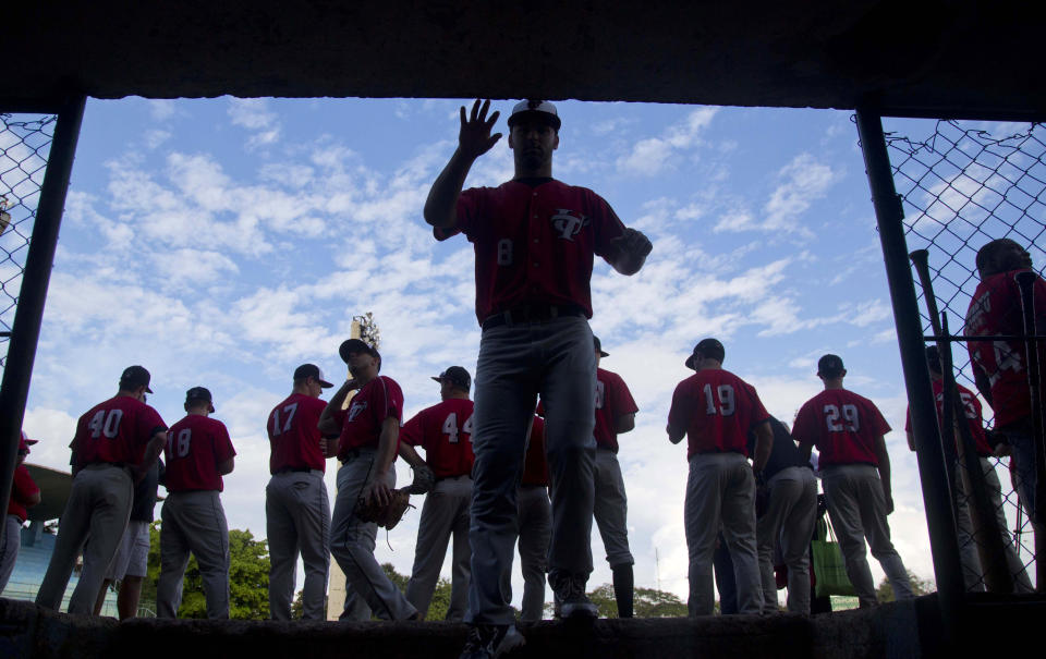 A baseball player from the University of Tampa reaches for the wall as he enters the dugout before the start of a game with Cuba's youth squad in Havana, Cuba, Wednesday, Jan. 15, 2014. Balls and strikes, not politics, ruled the day Wednesday at a baseball diamond in Havana, as last year's college championship team from the University of Tampa played an exhibition game against a Cuban youth squad. (AP Photo/Ramon Espinosa)
