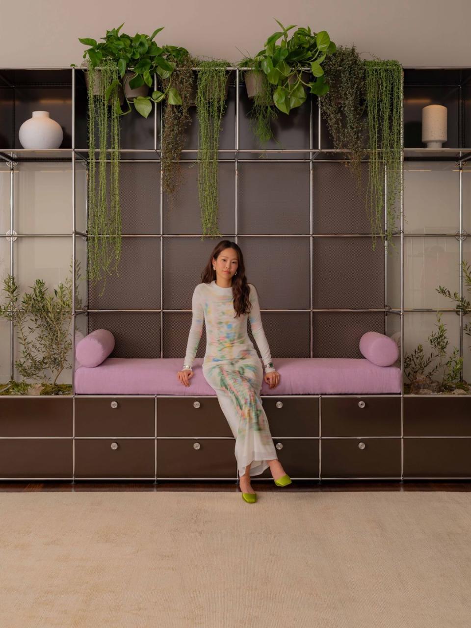 a woman posing in front of a wall with a pink object