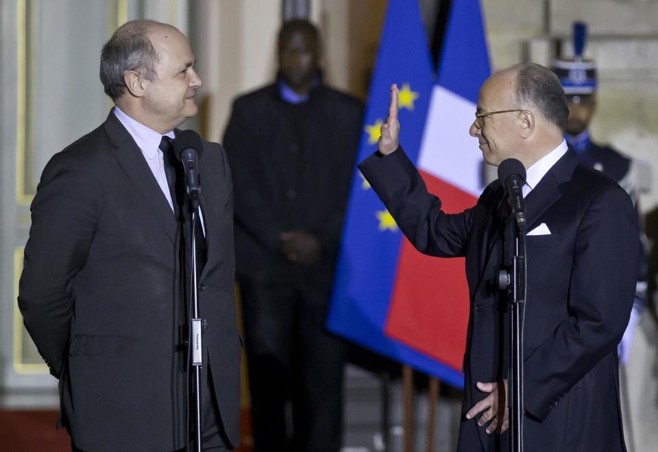 FILE - In this Dec.6, 2016 file photo, new French Prime Minister Bernard Cazeneuve, right, waves while newly appointed French Interior Minister Bruno Le Roux during a hand over ceremony in Paris. The French financial prosecutor's office has opened a preliminary investigation into a report that Interior Minister Bruno Le Roux hired his two daughters for 24 temporary parliamentary jobs. (AP Photo/Michel Euler, File)