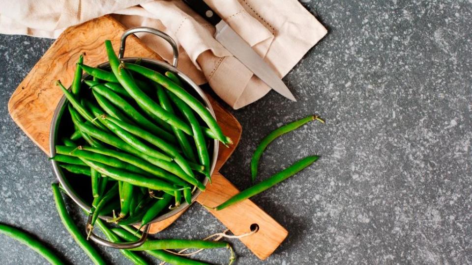 green beans in bowl on gray stone background top view copy space