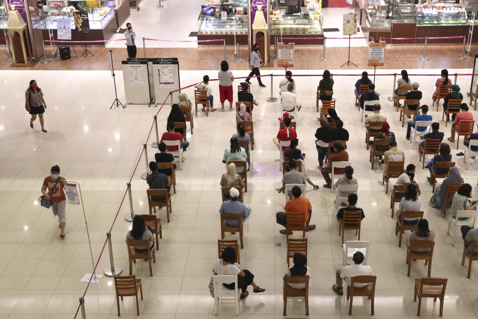 People sit spaced apart as a precaution against the new coronavirus outbreak while waiting for their turn to be allowed into a supermarket to shop, at AEON shopping mall in Tangerang, on the outskirts of Jakarta, Indonesia, Friday, May 22, 2020. Indonesia has seen a surge in coronavirus infections ahead of this this weekend's celebrations marking the end of Ramadan, raising questions about the commitment to the virus fight from both the government and the public. (AP Photo/Tatan Syuflana)