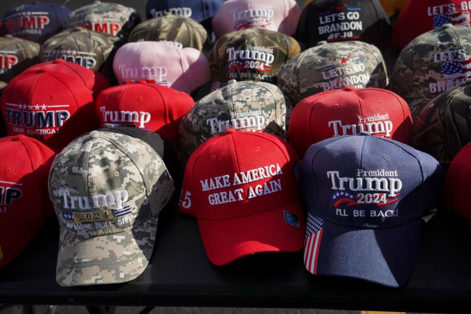 Hats sporting “Trump” and other right-wing political slogans are displayed on tables near Macomb Community College in Warren, Michigan, before a Donald Trump rally held there on Oct. 1, 2022.