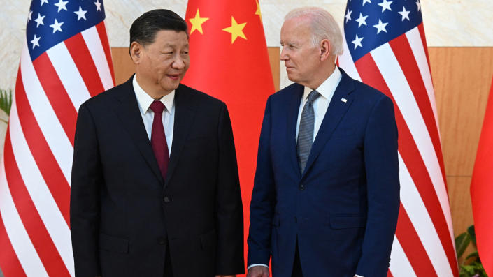 Chinese President Xi Jinping and President Biden stand in front of Chinese and American flags.