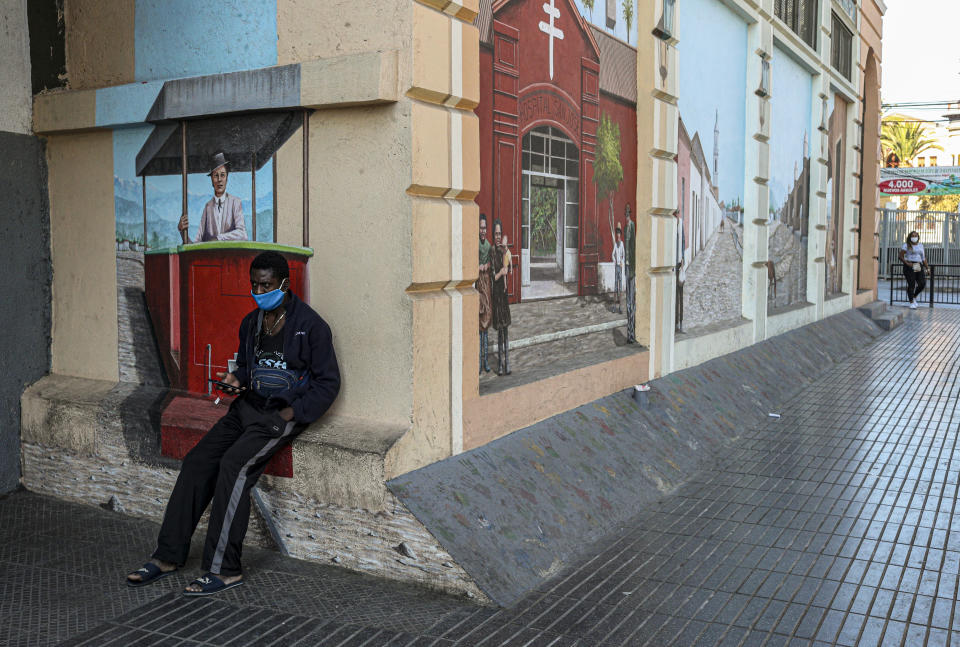 Un migrante haitiano está sentado frente a un mural en Santiago de Chile el 16 de mayo de 2020. (AP Foto/Esteban Felix)