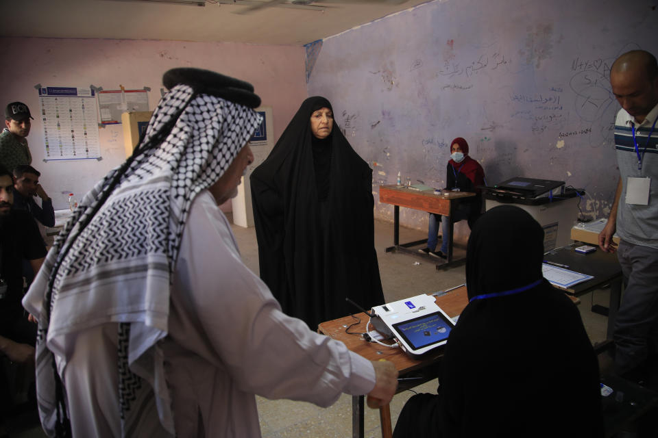 Iraqis gather to cast their vote at a ballot station in the country's parliamentary elections in Baghdad, Iraq, Sunday, Oct. 10, 2021. Iraq closed its airspace and land border crossings on Sunday as voters headed to the polls to elect a parliament that many hope will deliver much needed reforms after decades of conflict and mismanagement.. (AP Photo/Hadi Mizban)