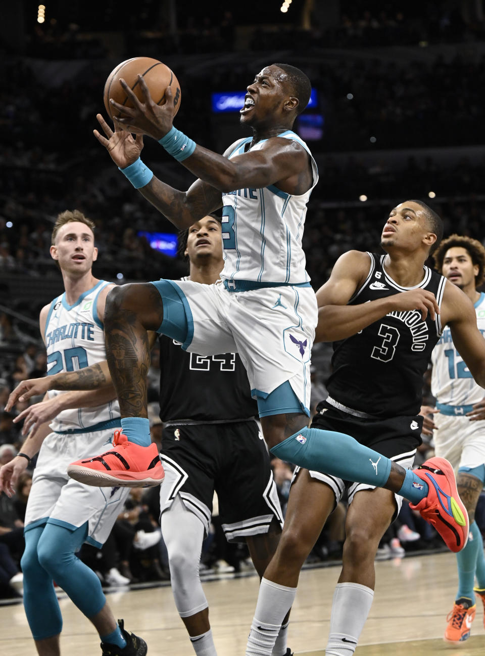 Charlotte Hornets' Terry Rozier, center, drives to the basket past San Antonio Spurs' Keldon Johnson, right, as Spurs' Devin Vassell and Hornets' Gordon Hayward, left, look on during the first half of an NBA basketball game, Wednesday, Oct. 19, 2022, in San Antonio. (AP Photo/Darren Abate)