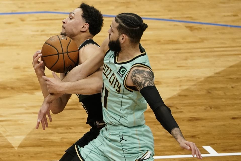 Milwaukee Bucks' Bryn Forbes and Charlotte Hornets' Cody Martin go after a loose ball during the first half of an NBA basketball game Friday, April 9, 2021, in Milwaukee. (AP Photo/Morry Gash)