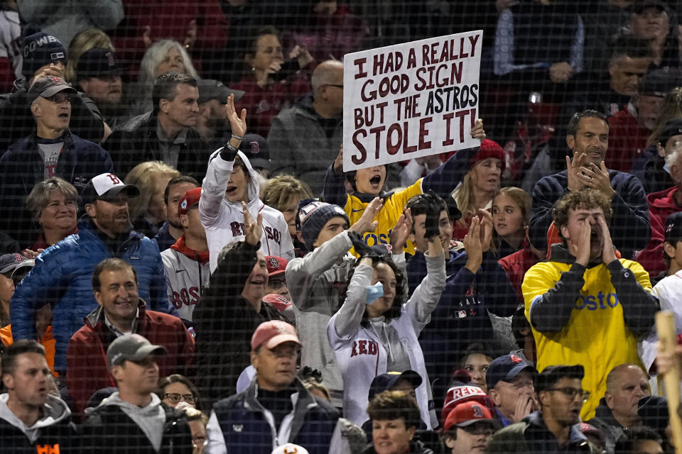 FILE - A Boston Red Sox fan holds a sign up during the second inning in Game 3 of baseball's American League Championship Series against the Houston Astros in Boston, in this Monday, Oct. 18, 2021, file photo. Before they could swing away against the Atlanta pitchers in the World Series, Jose Altuve and Houston Astros face another kind of heat. No, the cheating scandal that tainted their 2017 championship isn't going away anytime soon. (AP Photo/David J. Phillip, File)