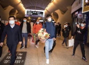 In this photo released by Xinhua News Agency, Jose Gonzalez, center, head coach of Wuhan FC, then known as Wuhan Zall, arrives with the team on their return to the railway station in Wuhan, central China's Hubei Province, on April 18, 2020. The club endured quite an ordeal last year after first being stranded in Spain on a preseason tour as its home city was overrun by the virus, and then fleeing the country just before the outbreak hit Europe hard. (Xiao Yijiu/Xinhua via AP)