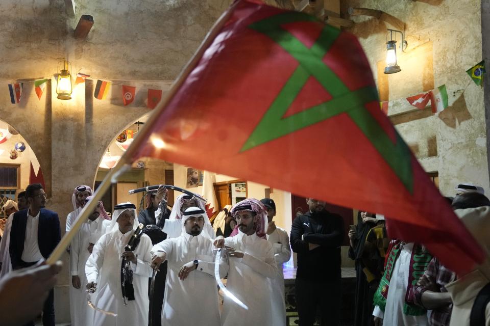 A man waves a Moroccan flag as people celebrate in the Souq in Doha, Qatar after Morocco beat Portugal in a World Cup quarterfinal soccer match at Al Thumama Stadium in Doha, Qatar, Saturday, Dec. 10, 2022. (AP Photo/Jorge Saenz)