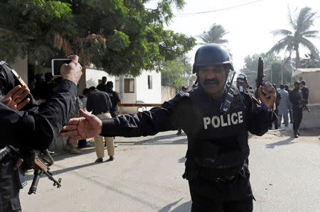 A Police officer stops people which take pictures with their cell phones, after an attack on the Chinese consulate, in Karachi, Pakistan November 23, 2018. REUTERS/Akhtar Soomro