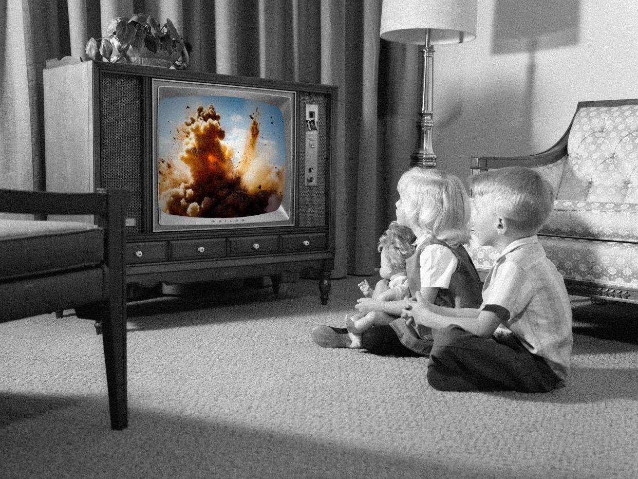 Two kids (in black and white) watching an explosion on TV (in color).