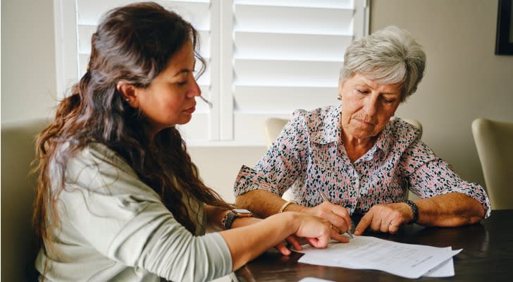 A woman signs some papers for the estate plan in the presence of her daughter. 