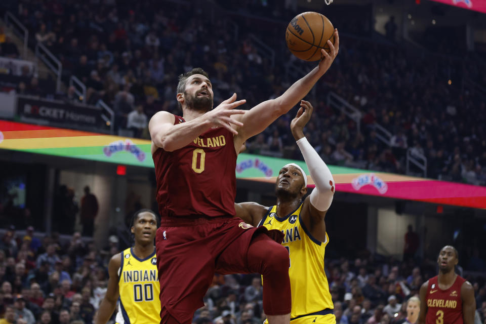 Cleveland Cavaliers forward Kevin Love (0) shoots against Indiana Pacers center Myles Turner and guard Bennedict Mathurin (00) during the first half of an NBA basketball game, Friday, Dec. 16, 2022, in Cleveland. (AP Photo/Ron Schwane)