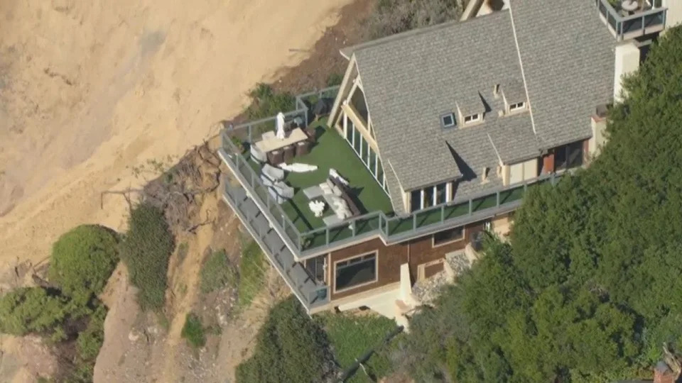 A home has come desperately close to falling into the ocean after a large chunk of coastline collapsed during a recent storm.