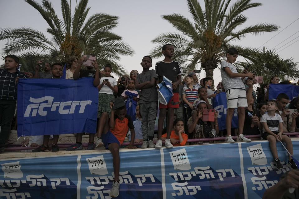 Supporters of the Likud party watch as former Israeli Prime Minister Benjamin Netanyahu delivers an election campaign speech from inside a modified delivery truck with a side wall replaced with bulletproof glass, in Beersheba, southern Israel, Tuesday, Sept. 13, 2022. As he hits the campaign trail for the fifth time in less than four years, Netanyahu is addressing supporters from the strange new vehicle dubbed the “Bibibus" after his popular nickname. (AP Photo/Ariel Schalit)